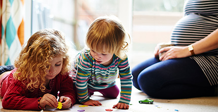 Pregnant mother playing with two young children