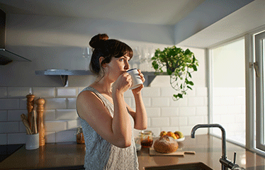 Woman looking out of the window holding a mug 